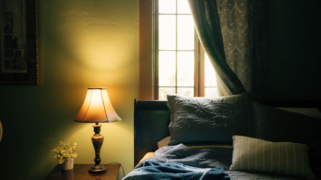 Cozy bedroom with warm lighting and no screen glow, illustrating healthy pre-sleep habits. Comparison of Night Mode vs Blue Light Glasses for eye protection