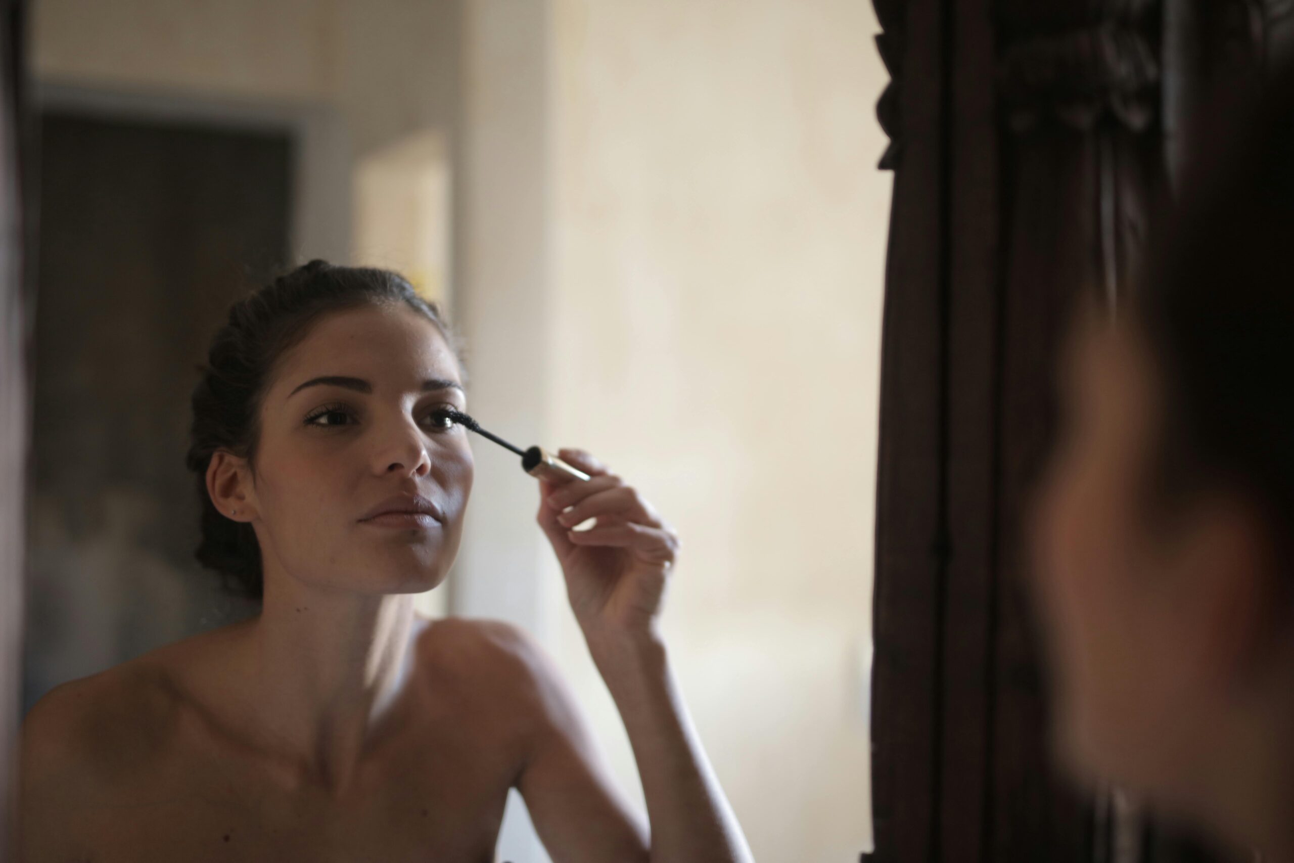Young woman applying mascara safely, symbolizing eye health and clean beauty habits