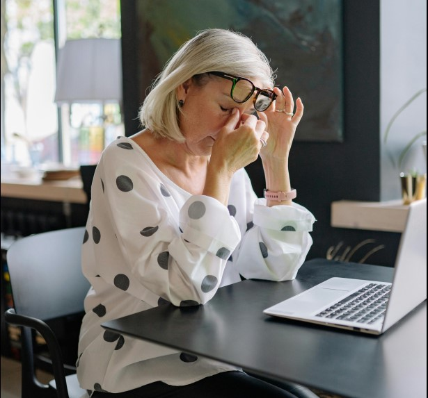 Person experiencing eye strain from long video calls at home office.