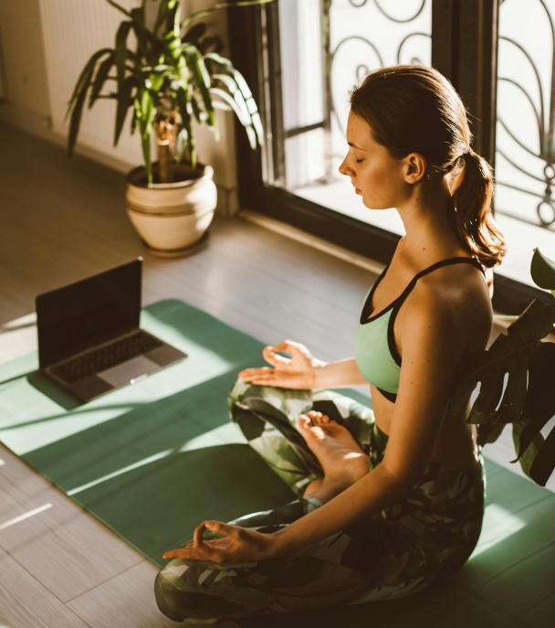 A person practicing eye relaxation near a window, demonstrating the blinking exercise and relaxation for eye health