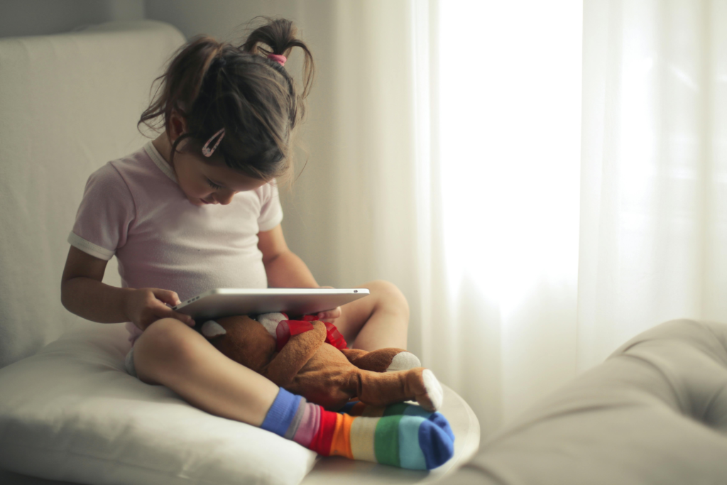 A young child using a tablet in daylight, showing modern screen habits and visual engagement.