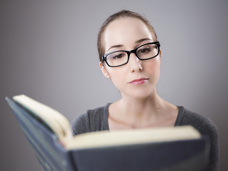 Middle-aged woman reading with glasses in natural daylight — representing age-related vision changes.”