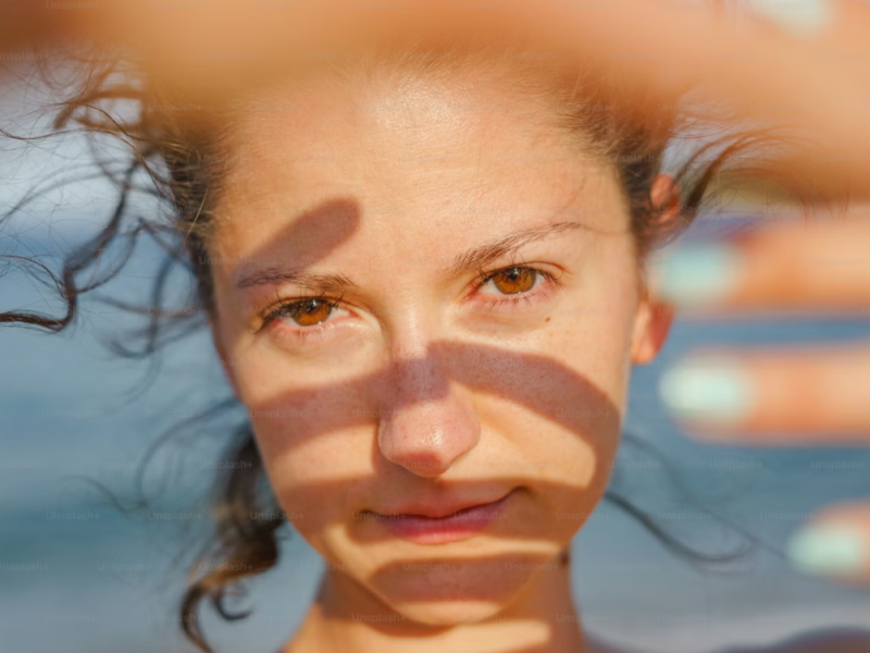 Person shielding eyes from bright light representing light sensitivity photophobia causes and relief.