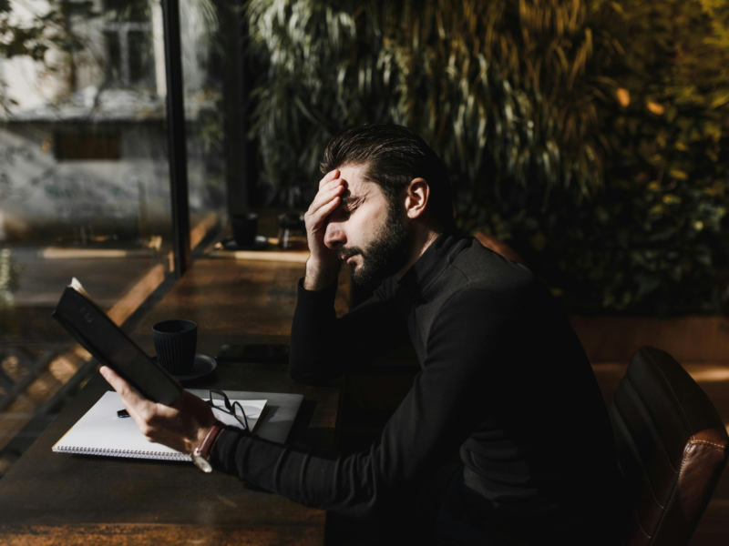 Person holding forehead with eyes closed in natural light, experiencing eye pressure without glaucoma symptoms.
